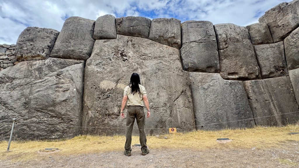 Anyextee stands before polygonal stonwork at Sacsayhuaman